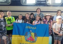 Діти Сіверської громади тримають прапор громади та стоять біля вагону