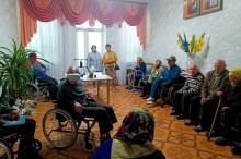Літні люди у кімнаті відпочинку беруть участь у заході, чоловік у колісному кріслі тестує VR-шолом