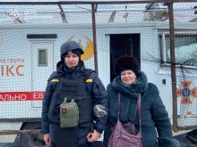 Рятувальник групи "Фенікс" тримає за руку жінку біля евакуаційної авівки