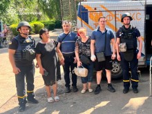 Четверо мешканців Дружківки стоять з рятувальниками біля евакуаційного автомобіля