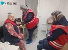 Фахівці Червоного Хреста міряють тиск жінці похилого віку