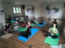 Йога для дітей: групове заняття з керівником гуртка у світлій залі з великими дзеркалами.