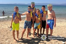 Хлопці і дівчата в дитячому таборі на південному морському узбережжі. Діти в масках для пірнання та з хустинками на шиї в жовто-синіх кольорах.