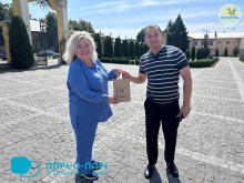 Представниця культурних установ Покровської громади, тримає пакет на якому написано Покровськ та дарує його фахівцю відділу культури  Шептицький