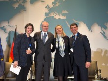 Групове фото чотирьох спікерів конференції НАТО, які стоять поруч і посміхаються на фоні карти світу та логотипу заходу.