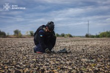 Опале листя. Працівник ДСНС ретельно придивляється у пошуках  мін, гранат або інших вибухонебезпечних предметів.