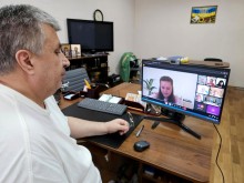 Представник військової адміністрації сидить за столом та слухає доповідача на семінарі