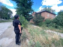 Правоохоронець стоїть через дорогу від пошкодженого двоповерхового будинку.