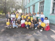 Спільне фото дітей та представників громад. Діти тримають жовті кульки. Жінки одягнені у вишиванки.