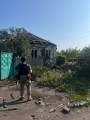Правоохоронець стоїть біля зруйнованого одноповерхового будинку після ворожого обстрілу.