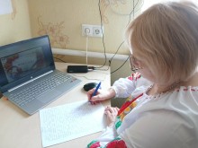 Учасник акції пише диктант перед екраном ноутбука