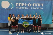 Група дівчат-спортсменок з Білозерської громади тримає прапор громади та позує на фоні банеру проєкту "Пліч-о-пліч"