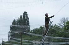 Військовий натягує антидронову сітку