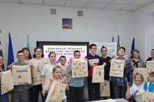Спільне фото організаторів та учасників заходу, які  тримають перед собою розписані власноруч екосумки