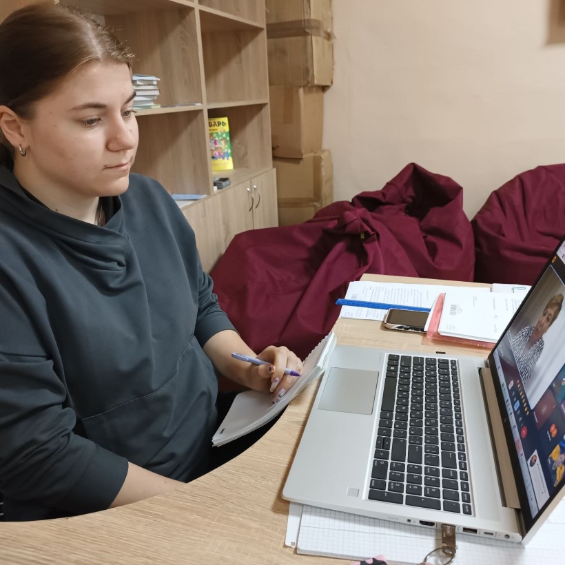 Фахівець військової адміністрації сидить за столом та слухає доповідачів, котрі висвітлюють актуальні питання на семінарі