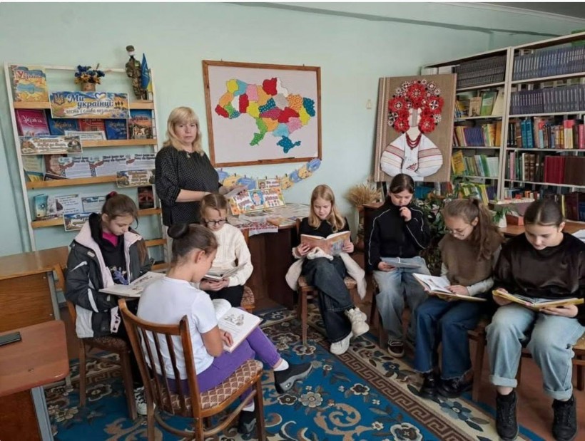 Група підлітків читає книжки у бібліотеці