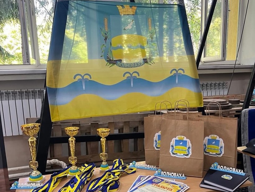 Кубки, медалі, грамоти та подарунками від Волноваської міської військової адміністрації. На задньому плані прапор громади.