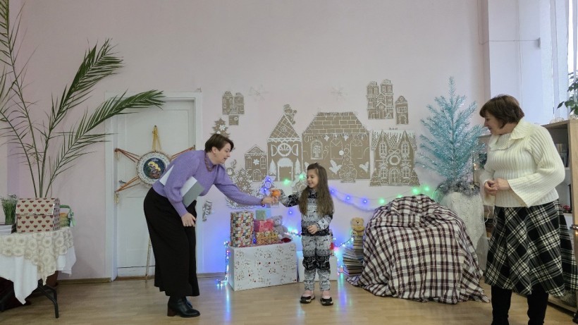 Дівчинка бере участь у програмі, тримаючи апельсин