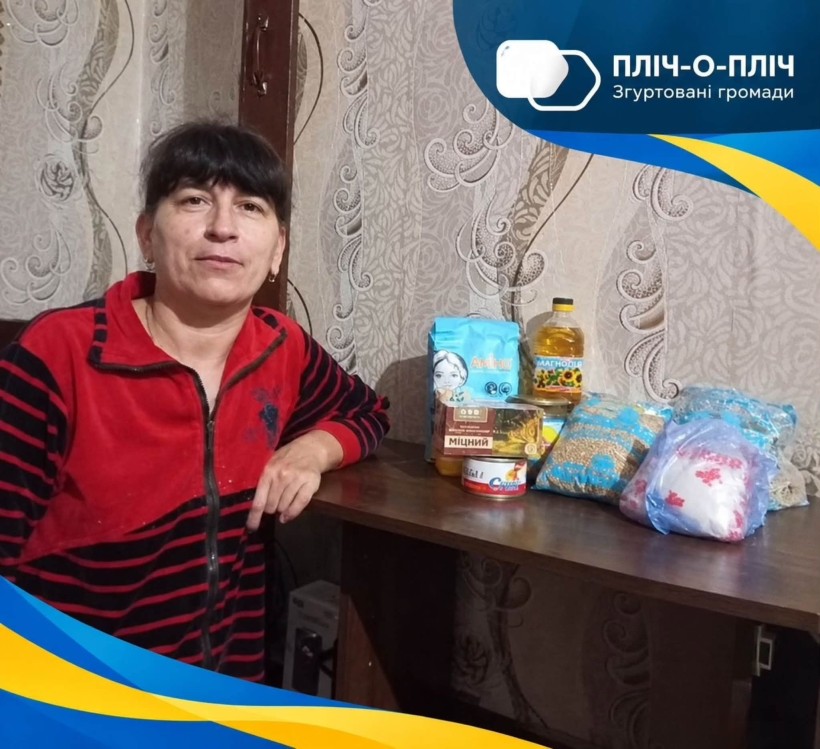 Жінка сидить біля столу з гуманітарною допомогою