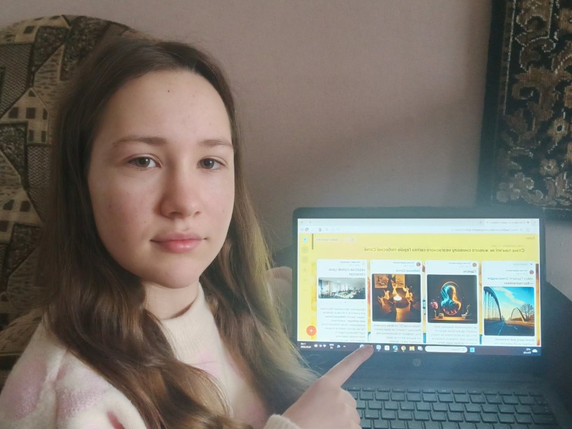 Дівчина показує на монітор, де включена падлет-дошка зі спільним проєктом