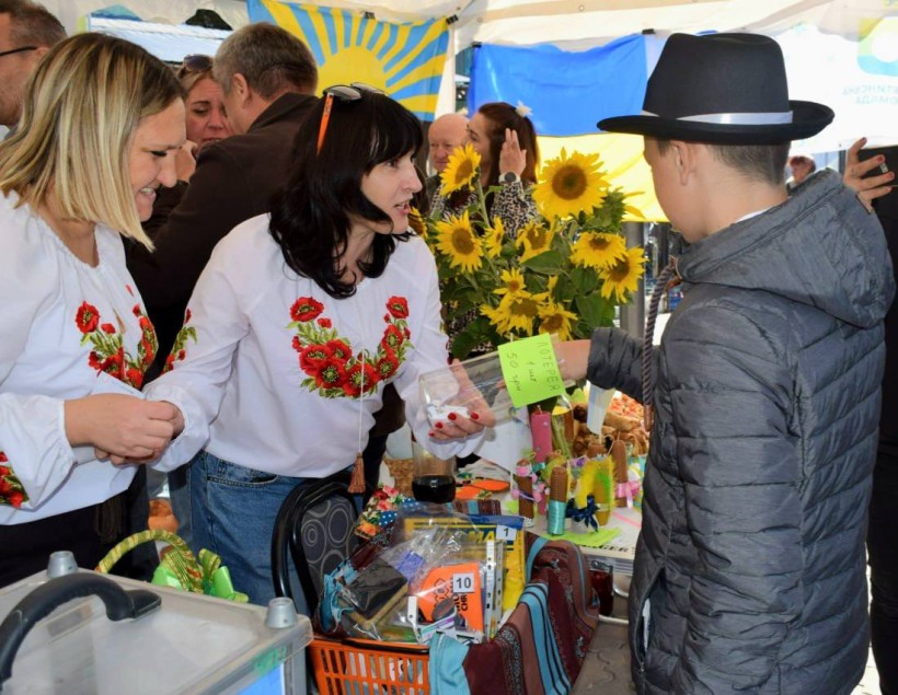 Ярмарок сувенірної продукції. Позаду прапори. На столах соняшники.