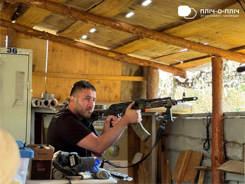 Учбовий бойовий бліндаж. Чоловік стоїть з вогнепальною зброєю, дивиться вперед.