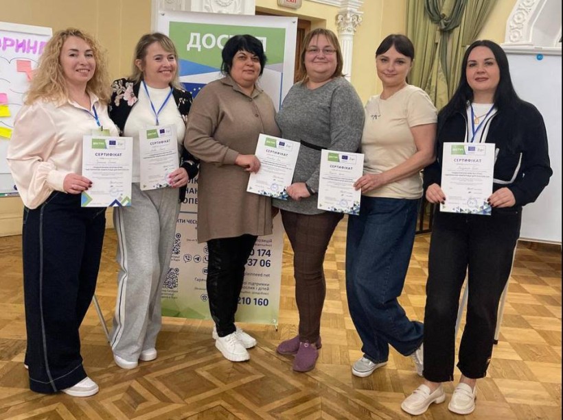 Шестеро жінок-педагогів Добропільської громади стоять у приміщенні після завершення тренінгу, тримаючи сертифікати про участь.