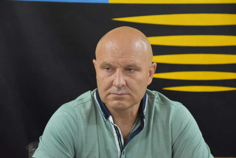 Учасник робочої групи. Сидить за столом, позаду прапор військової бригади.