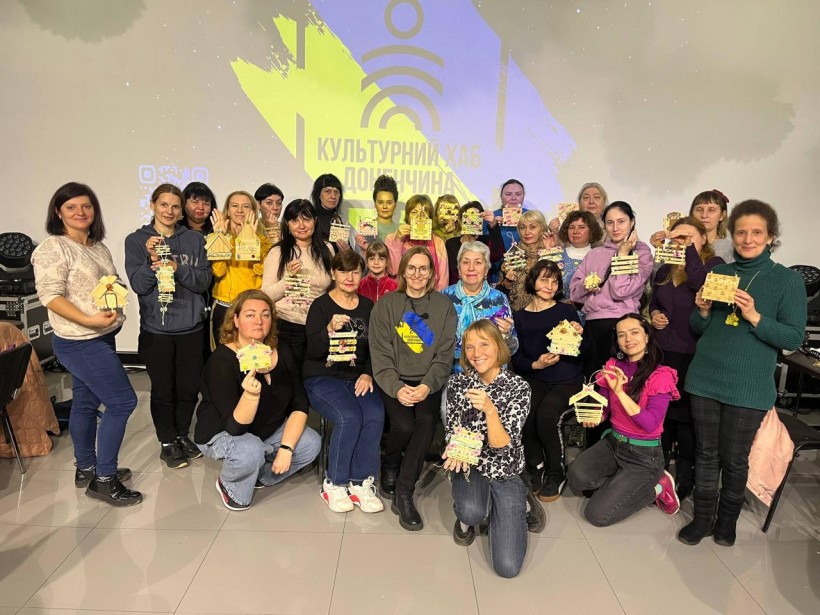 Дорослі відвідувачі на груповому фото показують поробки