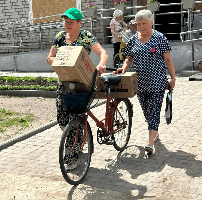 Жінки на велосипеді везуть коробки з гуманітарною допомогою