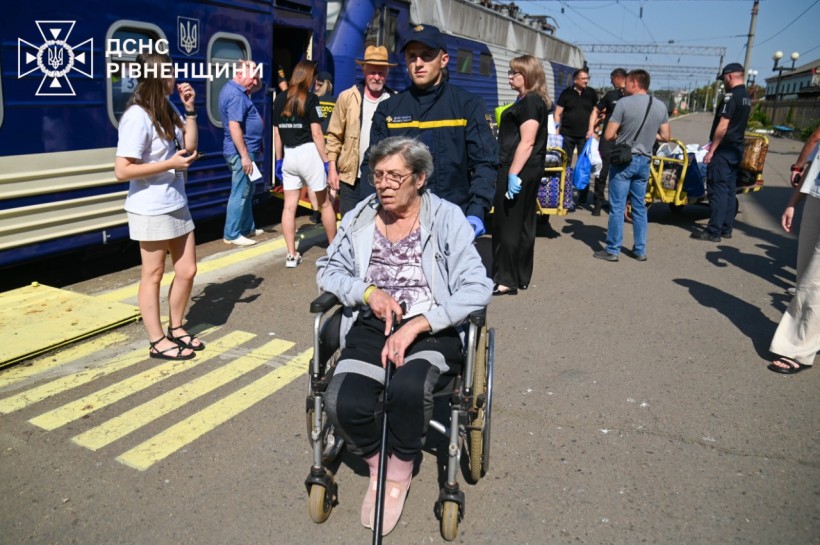 Рятувальник везе жінку на кріслі колісному на вокзалі