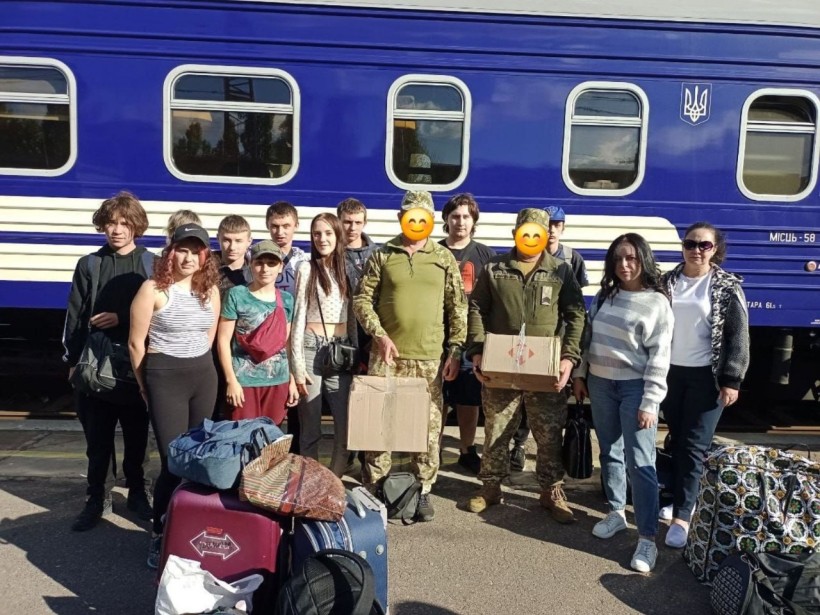 Група студентів біля потягу передає подарунки військовослуждовцям