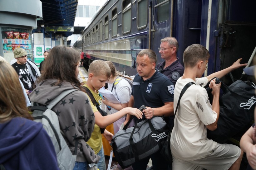 Діти Мангушської громади, біля вагону потяга. Охорона вокзалу допомогає дітям з речами.