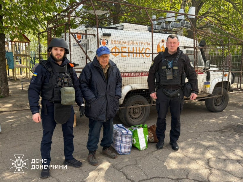 Евакуаційна група «Фенікс» та чоловік старшого віку біля евакуаційного автомобіля.