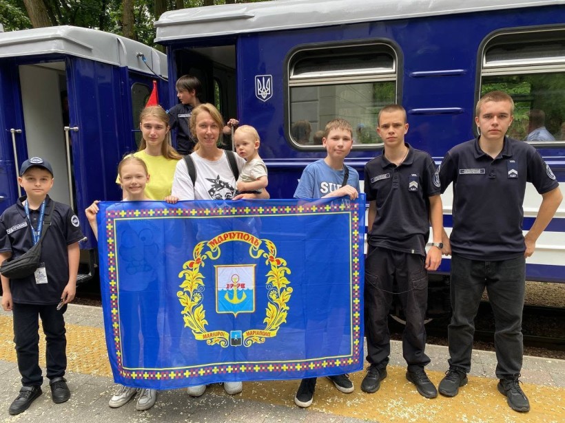 Фото родини з Маріуполя з прапором міста на дитячій залізниці