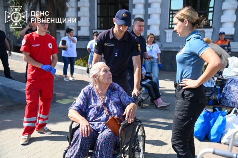 Рятувальник везе жінку в кріслі колісному, яку зустрів з евакуаційного потяга