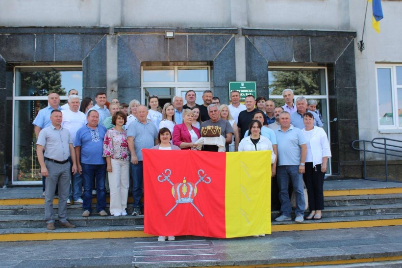 Спільне фото делегації біля адміністрації громади. На передньому плані тримають прапор Миколаївської громади.