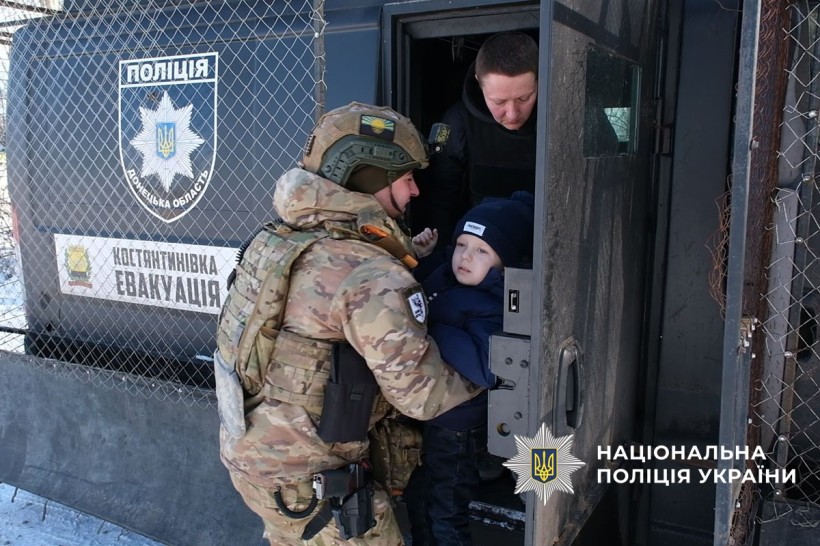 Евакуація. Поліцейські саджають дитину у броньований автомобіль.