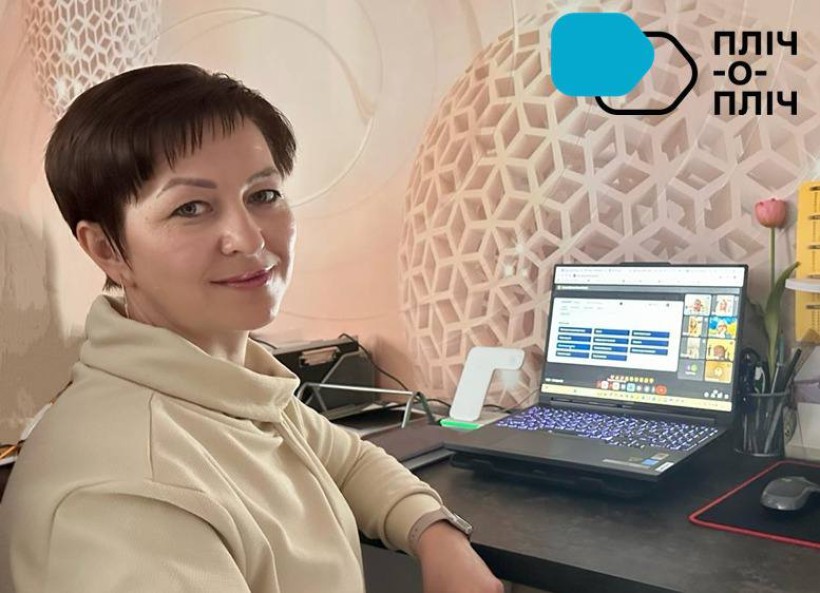 Усміхнена представниця громади сидить за столом біля ноутбука, на екрані монітора видно презентацію вебінару.