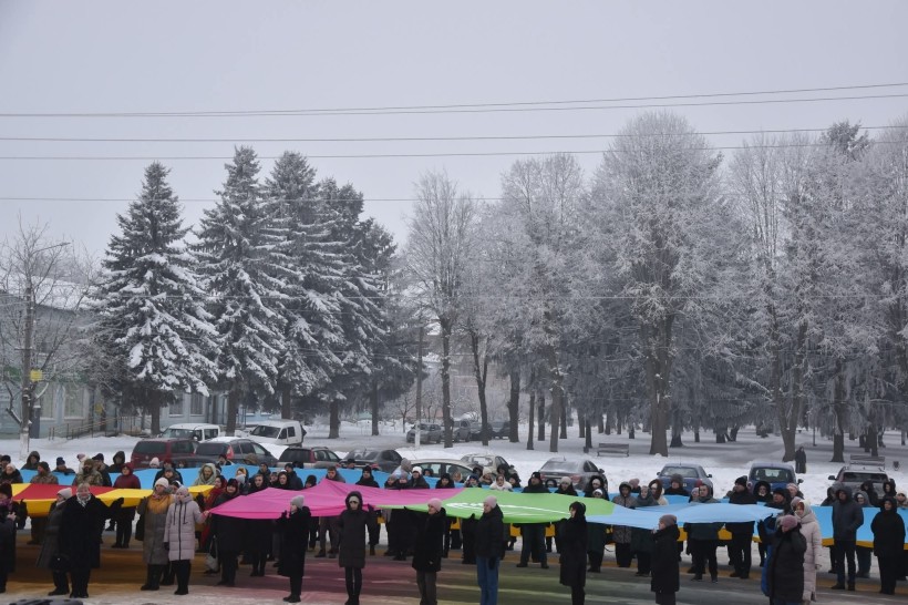 Учні та педагоги Бахмутської громади тримають прапор Бахмуту.
Дія на вулиці