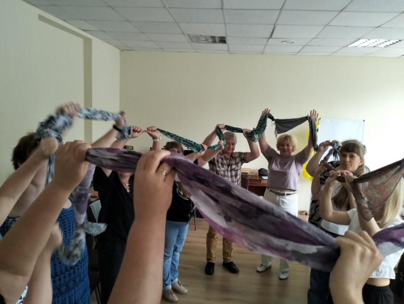 Група педагогів виконує вправу з тканинами, спрямовану на єднання, покращення комунікації.