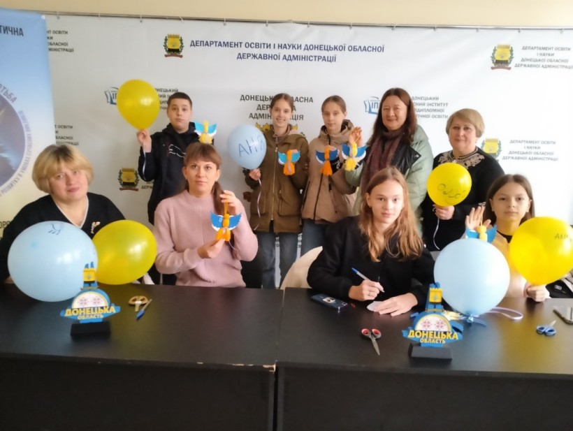 Діти та викладачі демонструють обереги для воїнів Збройних Сил України» в освітньому хабі «Донеччина». Усі тримають синьо-жовті кульки.