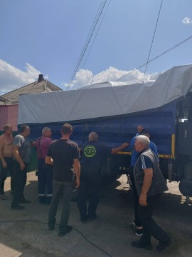 Чоловіки стоять біля вантажівки з комунальним майном Лиманської громади