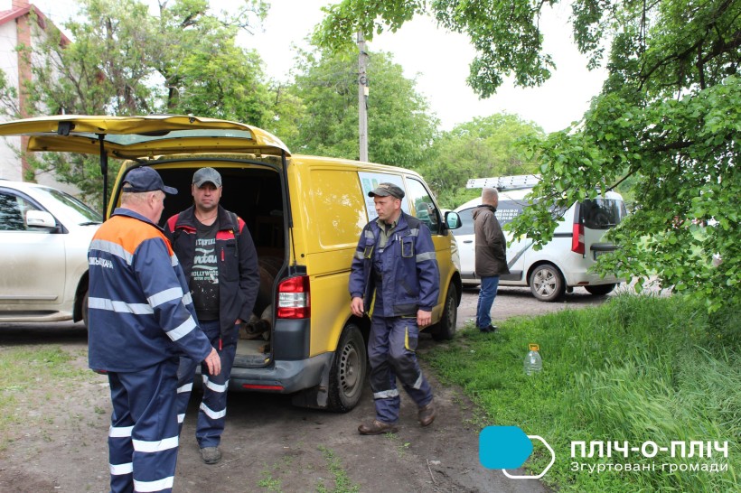 Група ремонтників у робочій формі стоять біля автівок