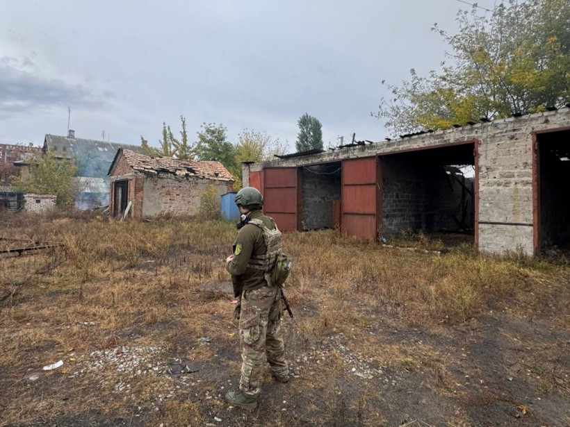 Правоохоронець стоїть біля гаражів, які зруйнували обстрілом окупанти