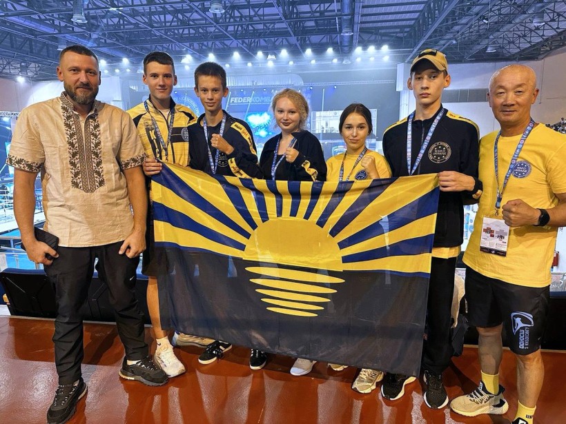 Спортсмени та тренери тримають прапор Донеччини після змагань