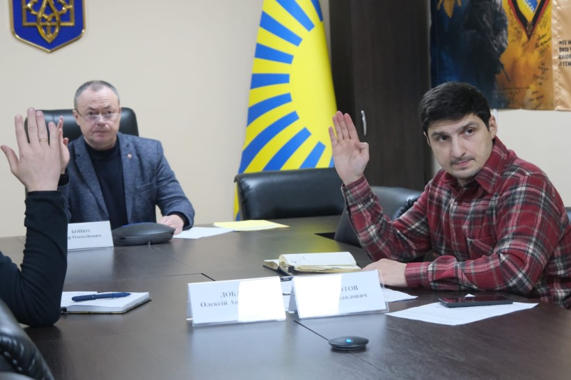 Члени комісії голосують, сидять за столом.