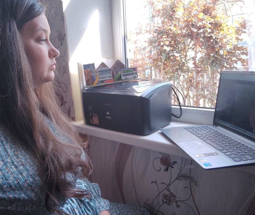 Представник військової адміністрації сидить за столом та слухає доповідача на семінарі