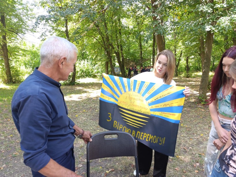 Дівчина тримає прапор Донецької області з написом "З вірою в Перемогу"