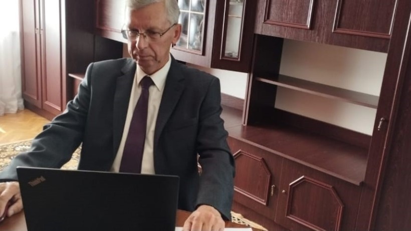 Учасник круглого столу у діловому костюмі сидить за робочим столом і ноутбуком